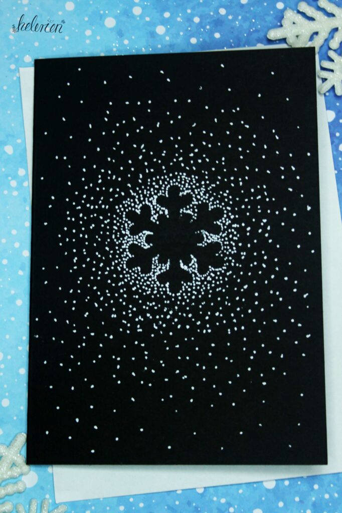 Eine Schneeflocke auf schwarzem Papier mit Punkten